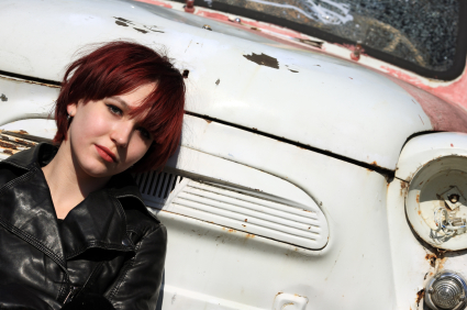 Girl wondering who buys junk cars while sitting in front of hers.