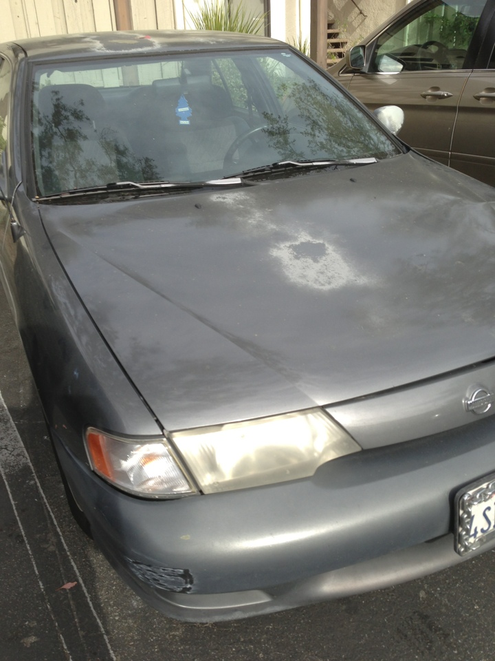 Older car with paint problems sitting.